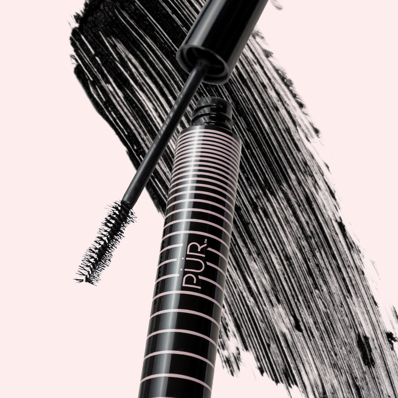 Bio Charged mascara tube with pink stripes and wand over bold black brush strokes on a pale pink background.