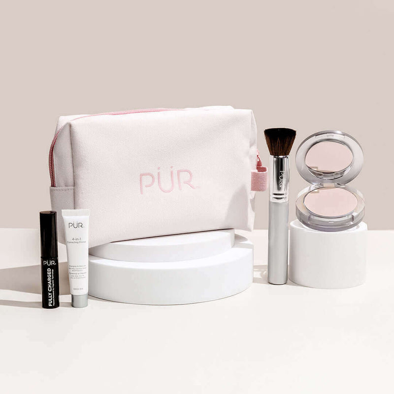 PÜR - Piece Start Now Set: Limited Edition  - Mascara, primer, brush, and powder arranged in front of bag against a beige background.